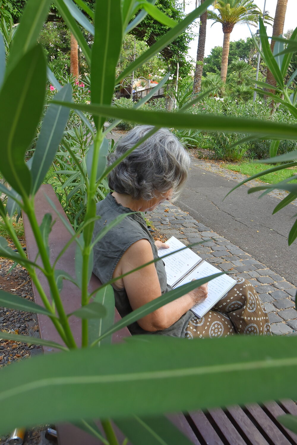 Rosalía Martín Expósito escribiendo en un cuaderno entre hojas verdes